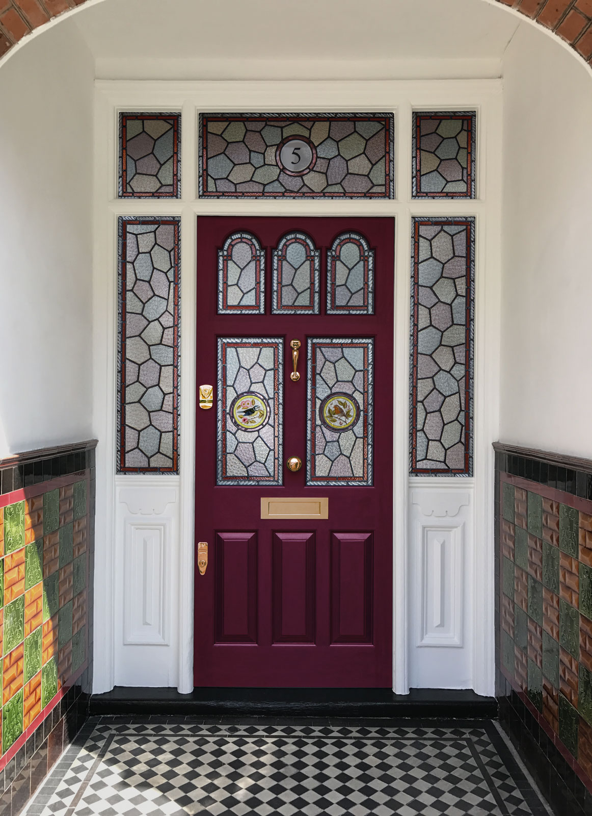 Dark red door in our Mulberry shade, featuring intricate stained glass panels